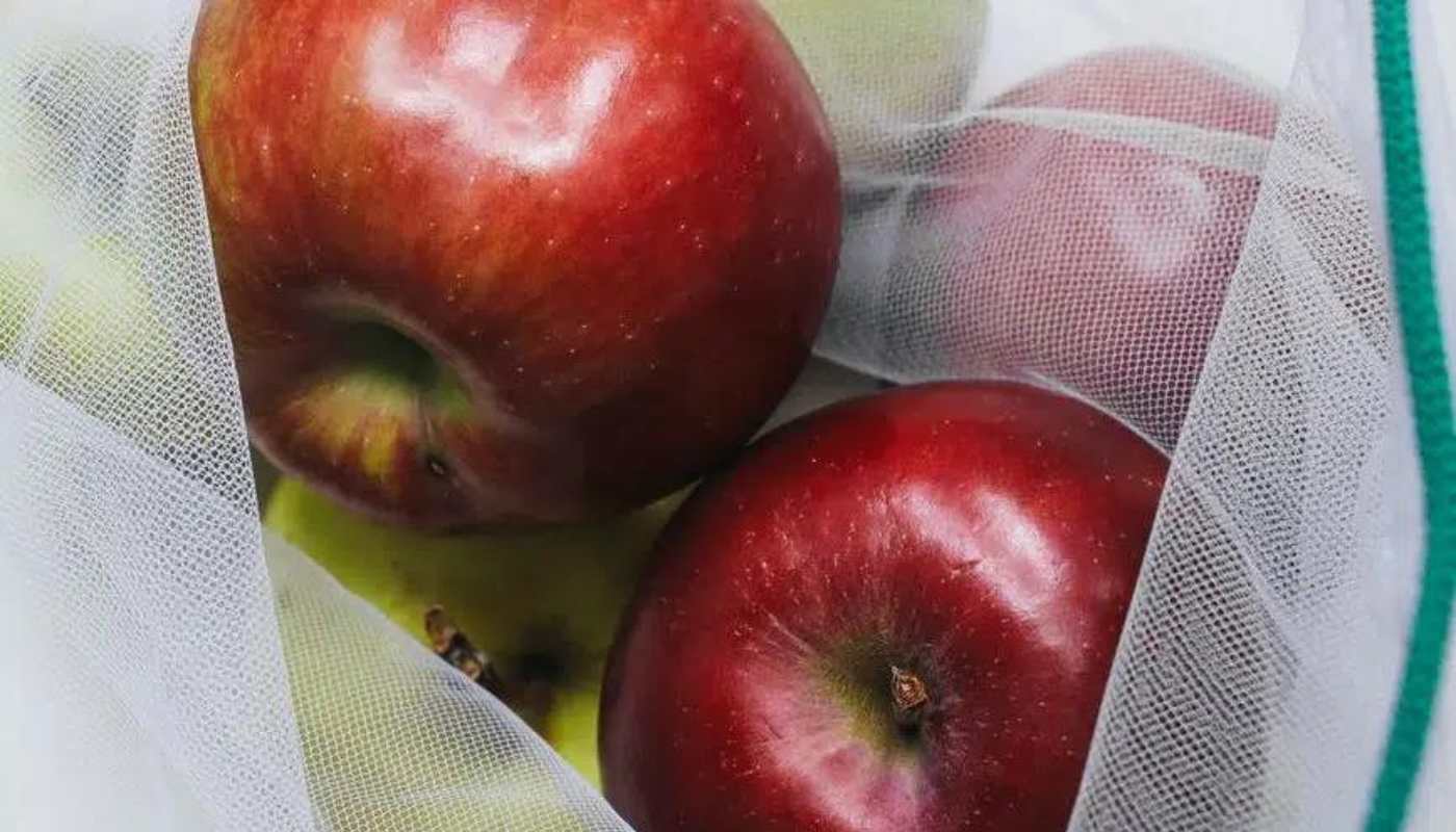 Red apples in a white mesh produce bag