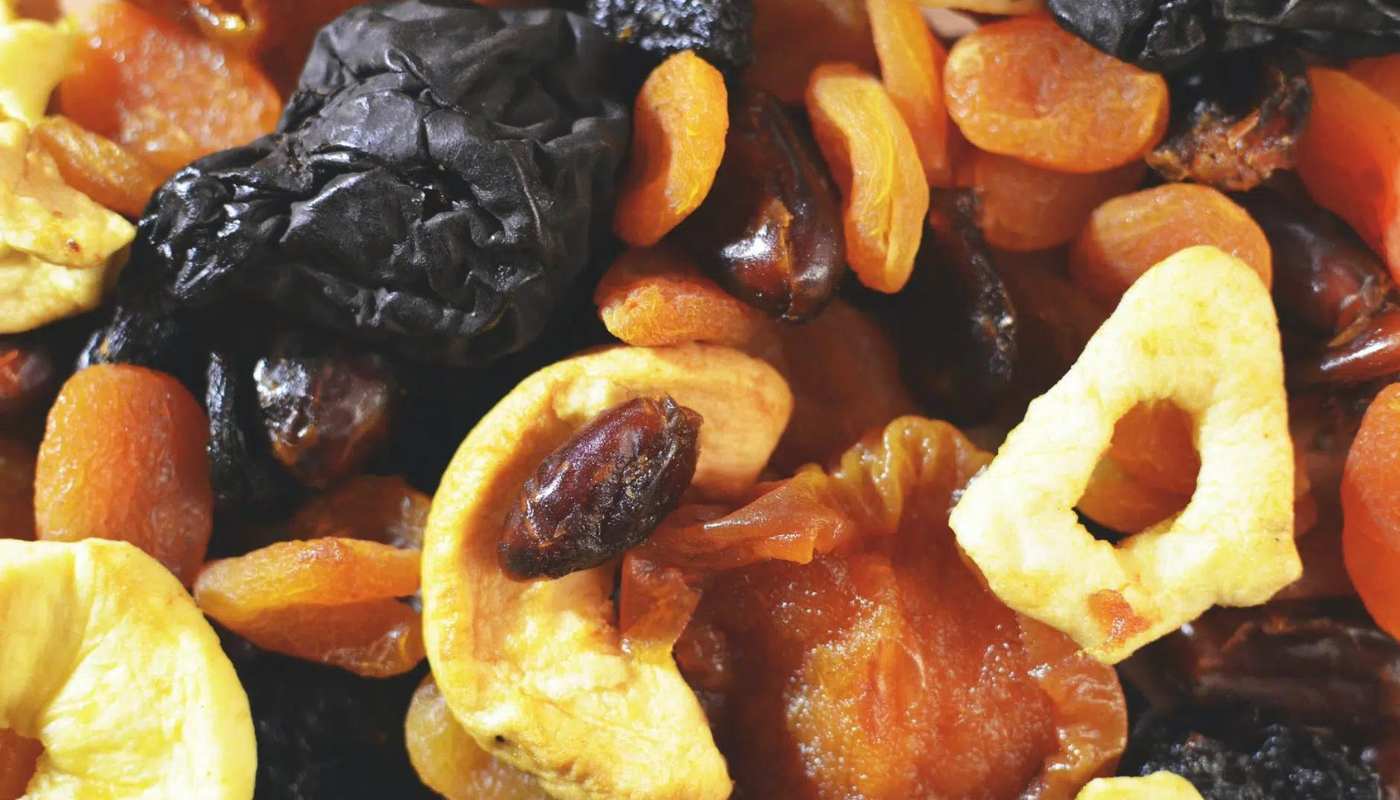 A close-up mix of dried apricots, prunes, dates and apple rings
