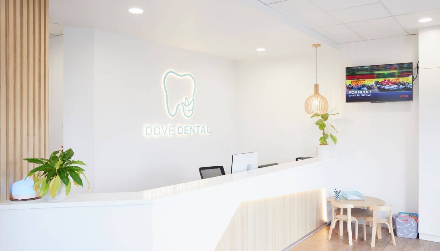 The Dove Dental Waurn Ponds reception and waiting area, with timber panelling, plants and a wall-mounted television