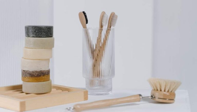 Bamboo toothbrushes standing upright in a glass jar on a bathroom counter