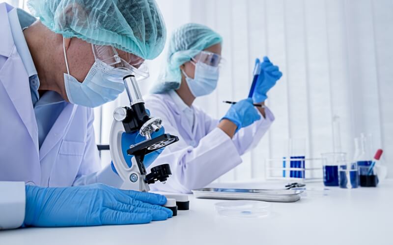 Researchers in a laboratory working with a microscope and test tubes