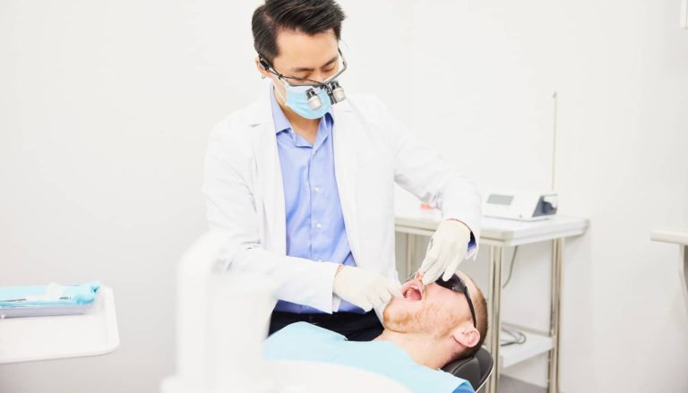 A dentist examining a patient reclined in the dental chair