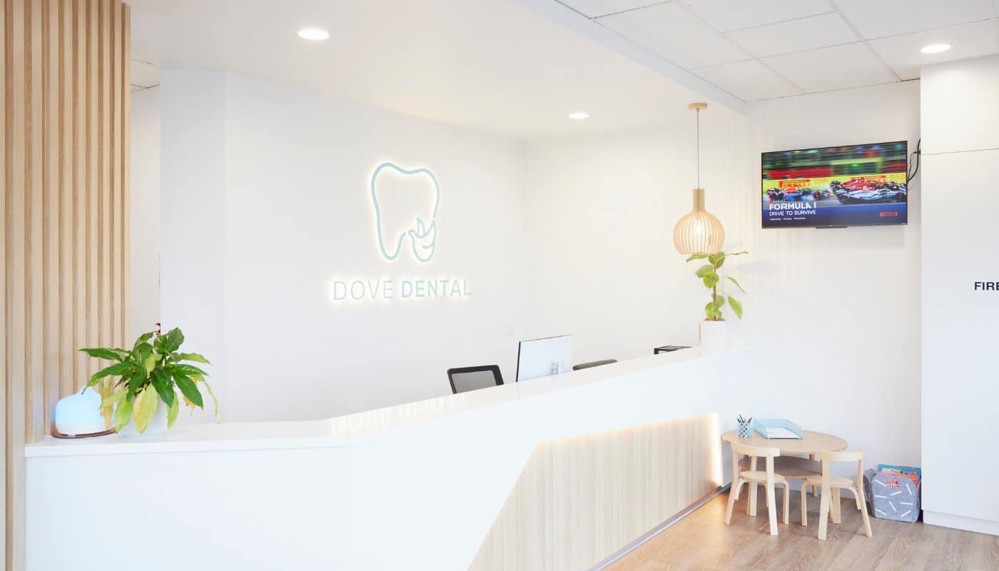 The Dove Dental reception desk at Waurn Ponds, with the illuminated practice logo on the wall behind it