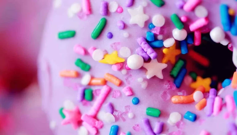 Close-up of a pink-iced doughnut covered in coloured sprinkles